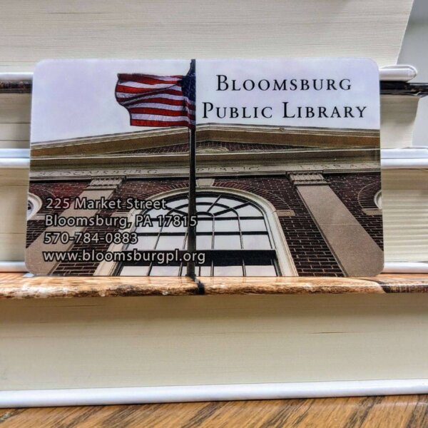 A Bloomsburg Public Library card against a pile of books