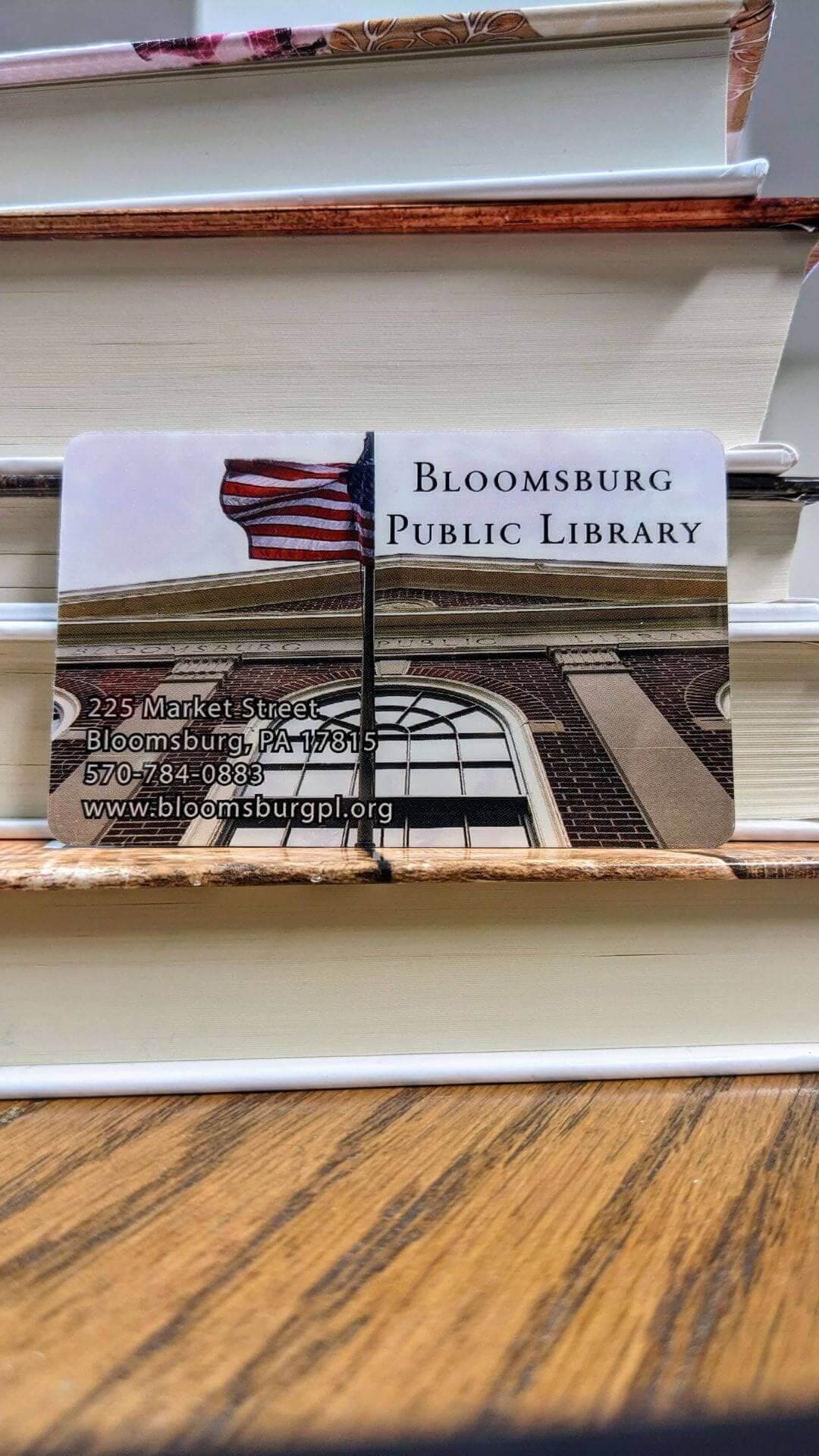 A Bloomsburg Public Library card against a pile of books
