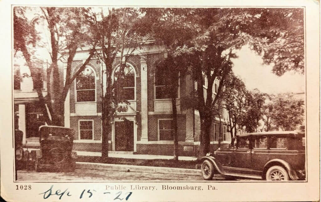 Postcard dated 1927, showing the original Library building and automobiles parked in front.