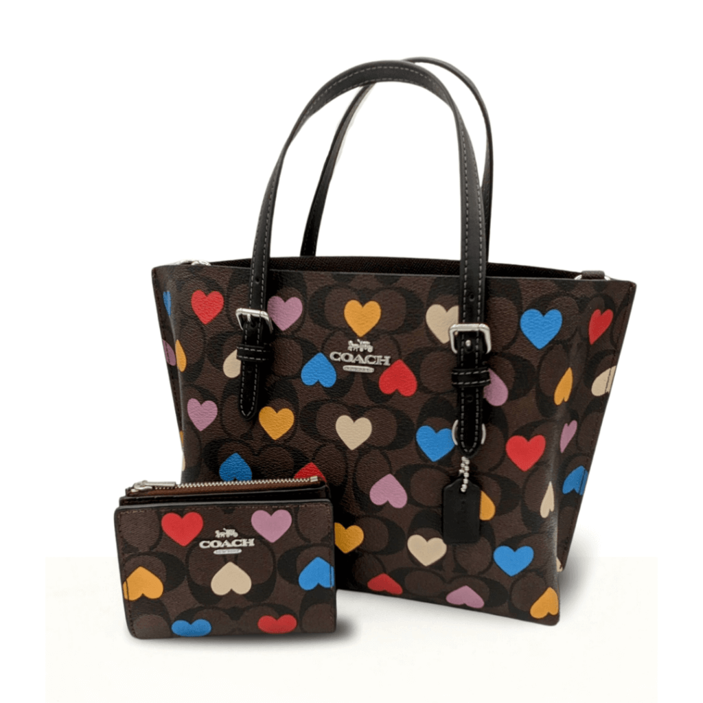 A Coach Mollie Signature tote bag adorned with a multicolored heart print on a dark background, paired with a matching coin purse, showcasing a playful and stylish design.